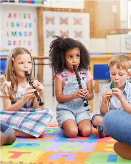 3 kids sitting on a floor playing clarinet