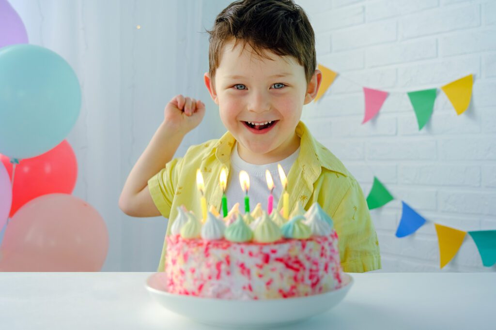 little boy smiling with a birthday cake in front of him