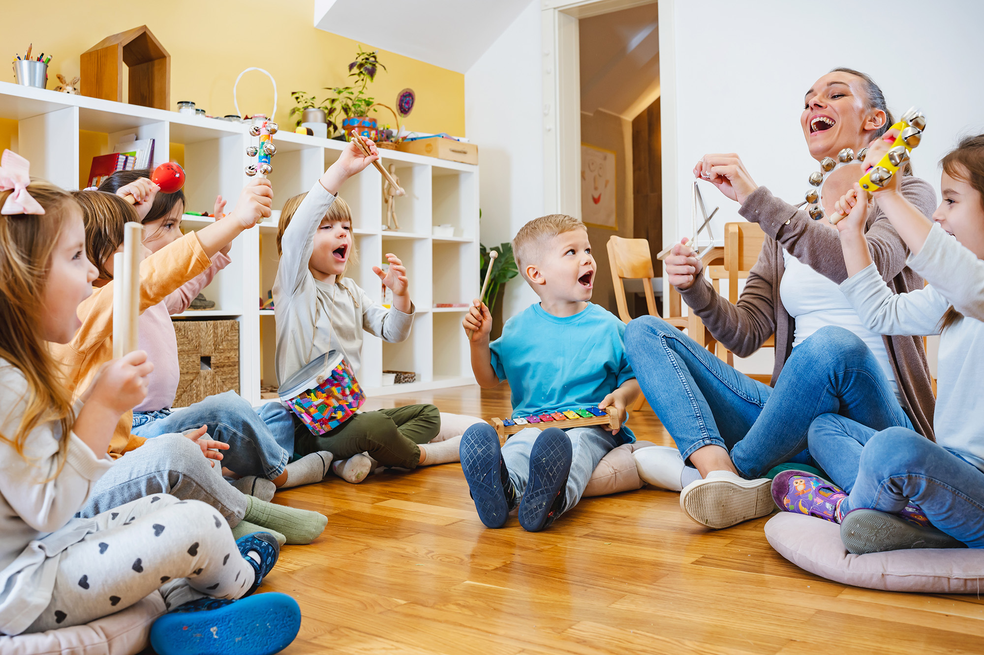 music teacher and children sitting in a circle on the floor smiling